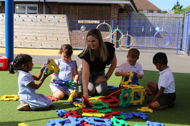 Tara leading an outdoor learning session with Early Years pupils using large colourful construction toys