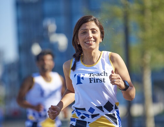 A woman jogging wearing Teach First running vest