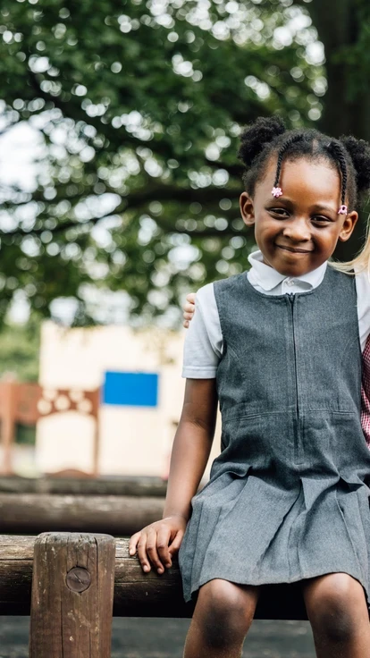 Image of two primary pupils sat next to each other with their arms over one another's shoulder