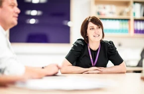 Image of teachers sat at desk smiling