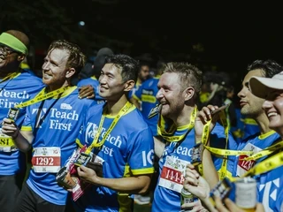 Smiling runners in Teach First shirts celebrating with medals after completing Run the River 2025.