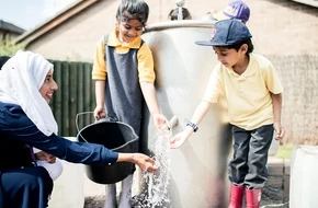 A teach and her students play with a fountain